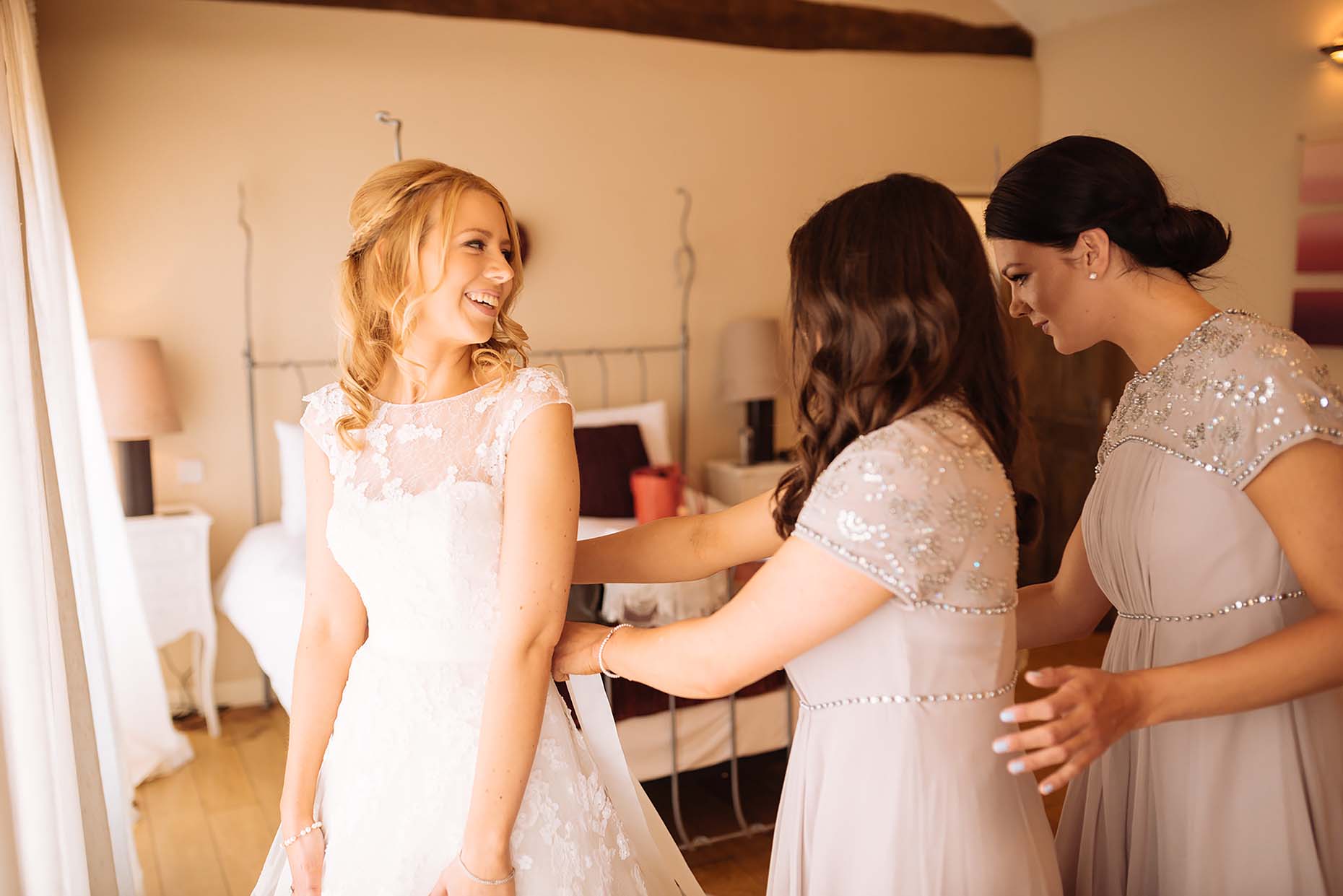 bride-with-bridesmaids-putting-on-dress-northampton-wedding-photographer-emma-dodmoor-12